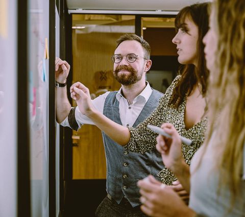 Three figures gathered around a whiteboard