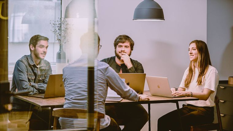 Three people having a meeting around a desks