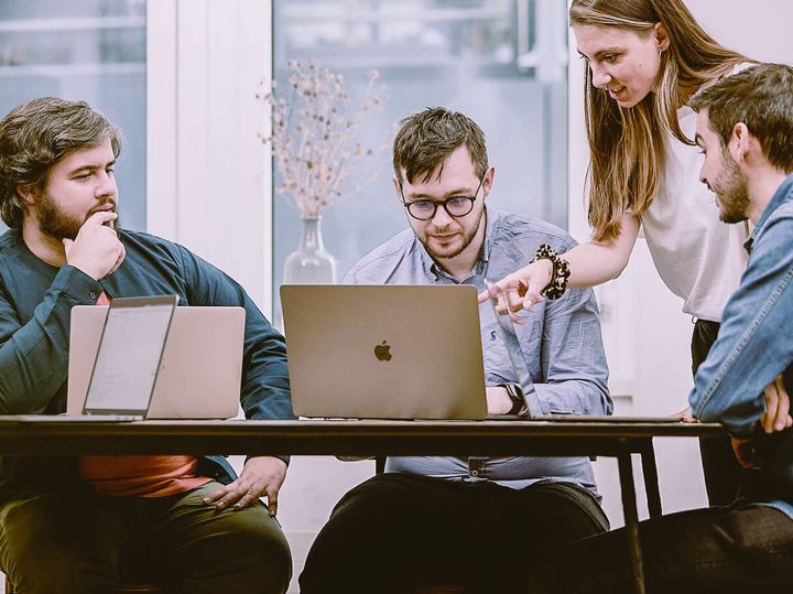 Four team members having a meeting around a laptop