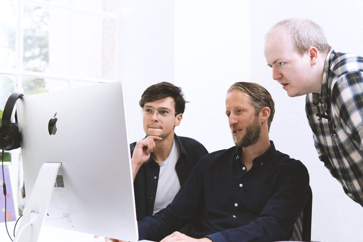 Three team members gathered around a computer