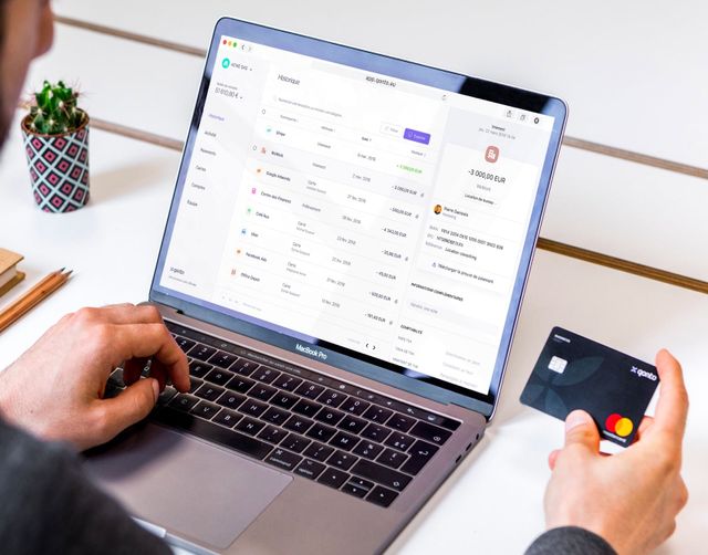 Man holds a credit card while looking at the Qonto web application